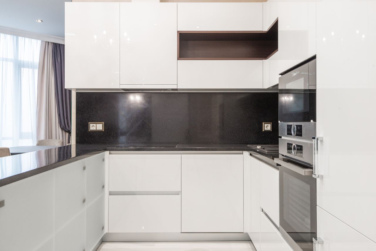 Sleek and clean modern kitchen with minimalist white cabinetry and black accents.